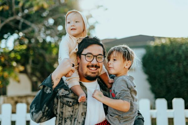 Dad smiles while holding two kids